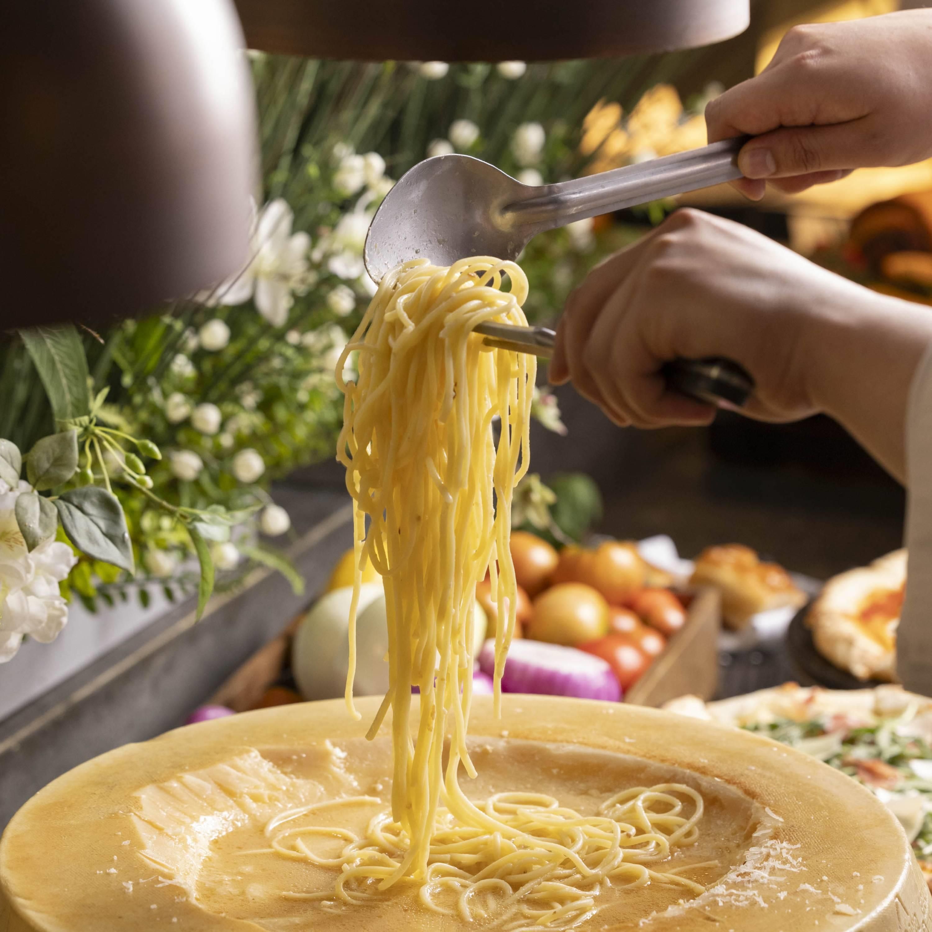 A person serving spaghetti onto a plate.