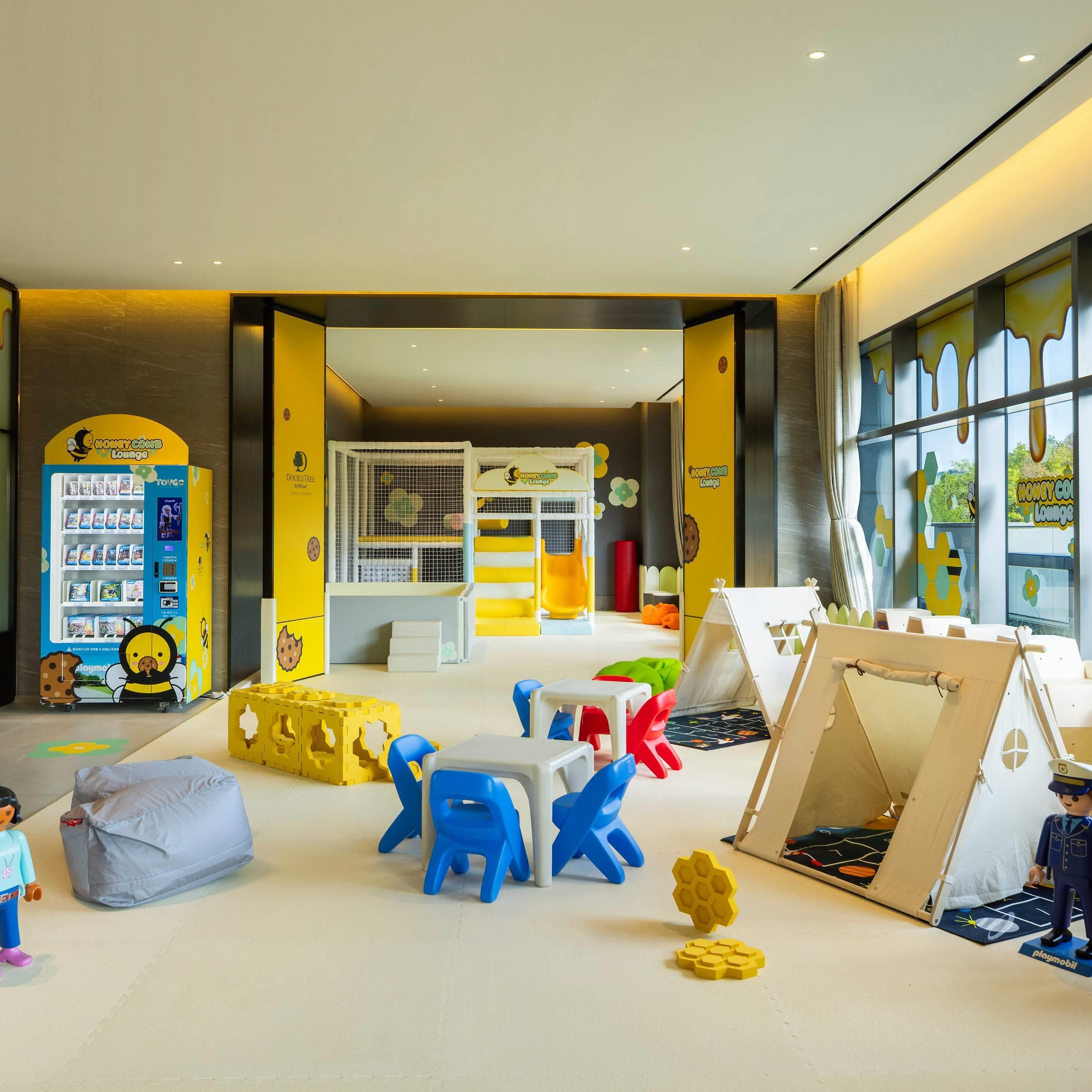 A children's play area with a vending machine, play tables, and a tent.