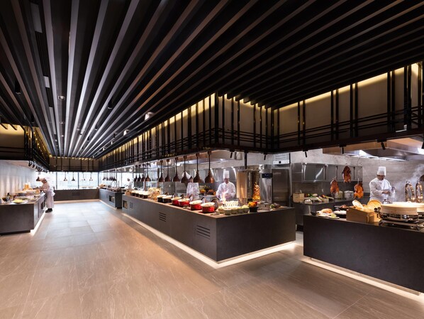 A modern kitchen with chefs preparing food, stainless steel appliances, and a high ceiling with linear lighting. - Doubletree By Hilton Seoul Pangyo (Seongnam)