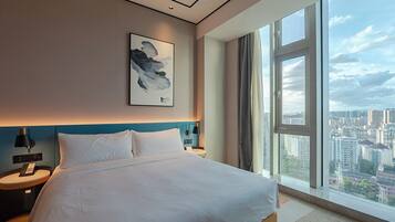 Una habitación de hotel moderna con una cama grande, vistas a la ciudad y un cuadro en la pared.