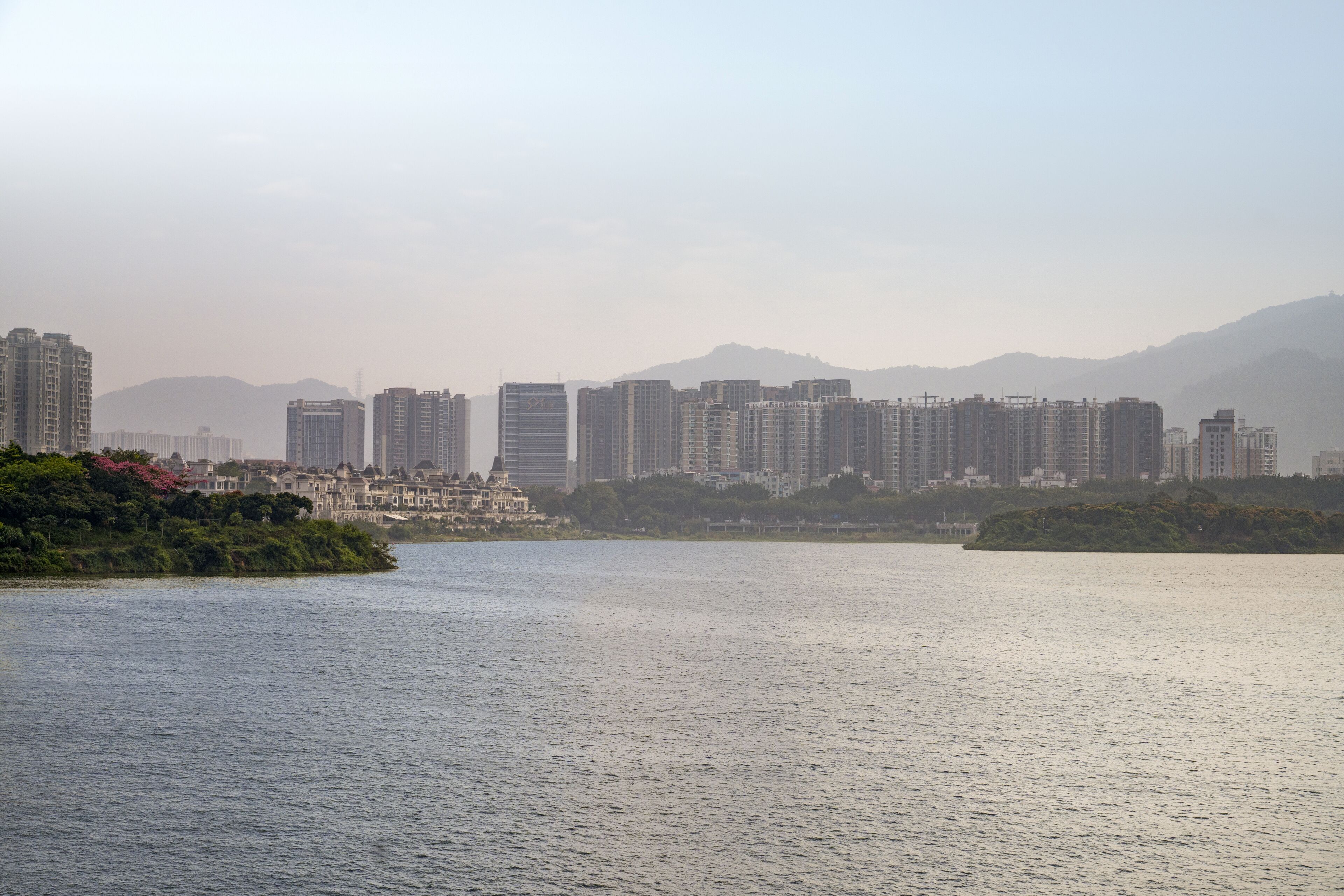 A waterfront cityscape with high-rise buildings and a calm river.