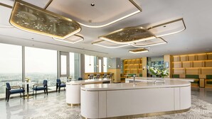 A modern hotel lobby with a central island, seating area, and large windows offering city views. - Hilton Garden Inn Shenzhen Airport (Shenzhen)