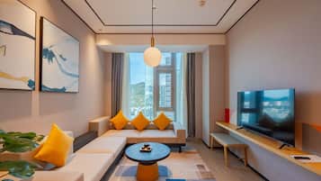 A modern living room with a sofa, a coffee table, a TV, and a large window with a city view.