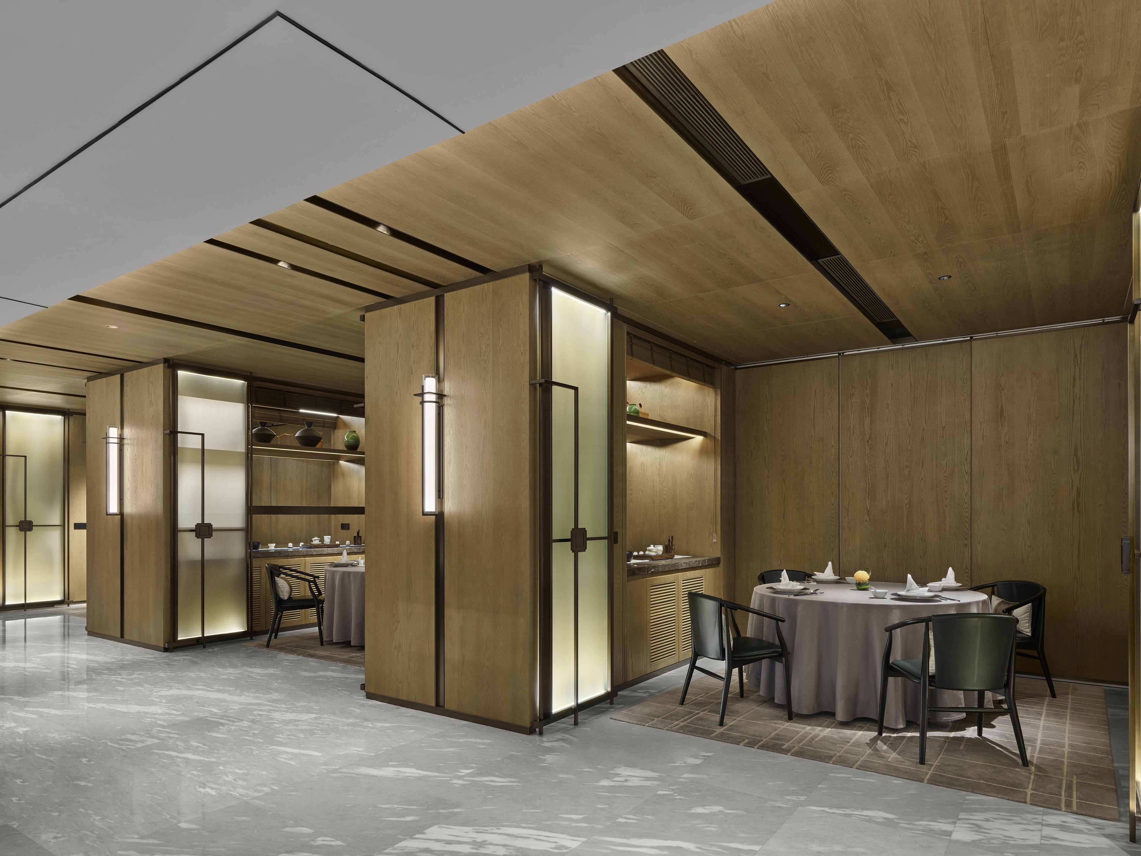 A modern interior with a dining area, wooden panel walls, and a marble floor.