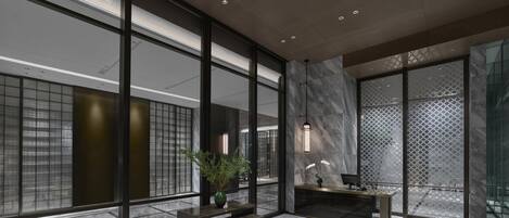 A modern lobby with large windows, a reception desk, and a seating area.