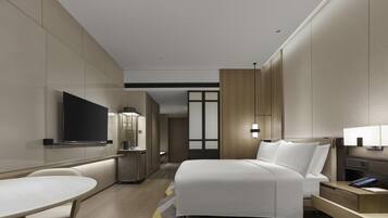 A modern hotel room with a bed, bedside table, lamp, TV, and a desk with chair.