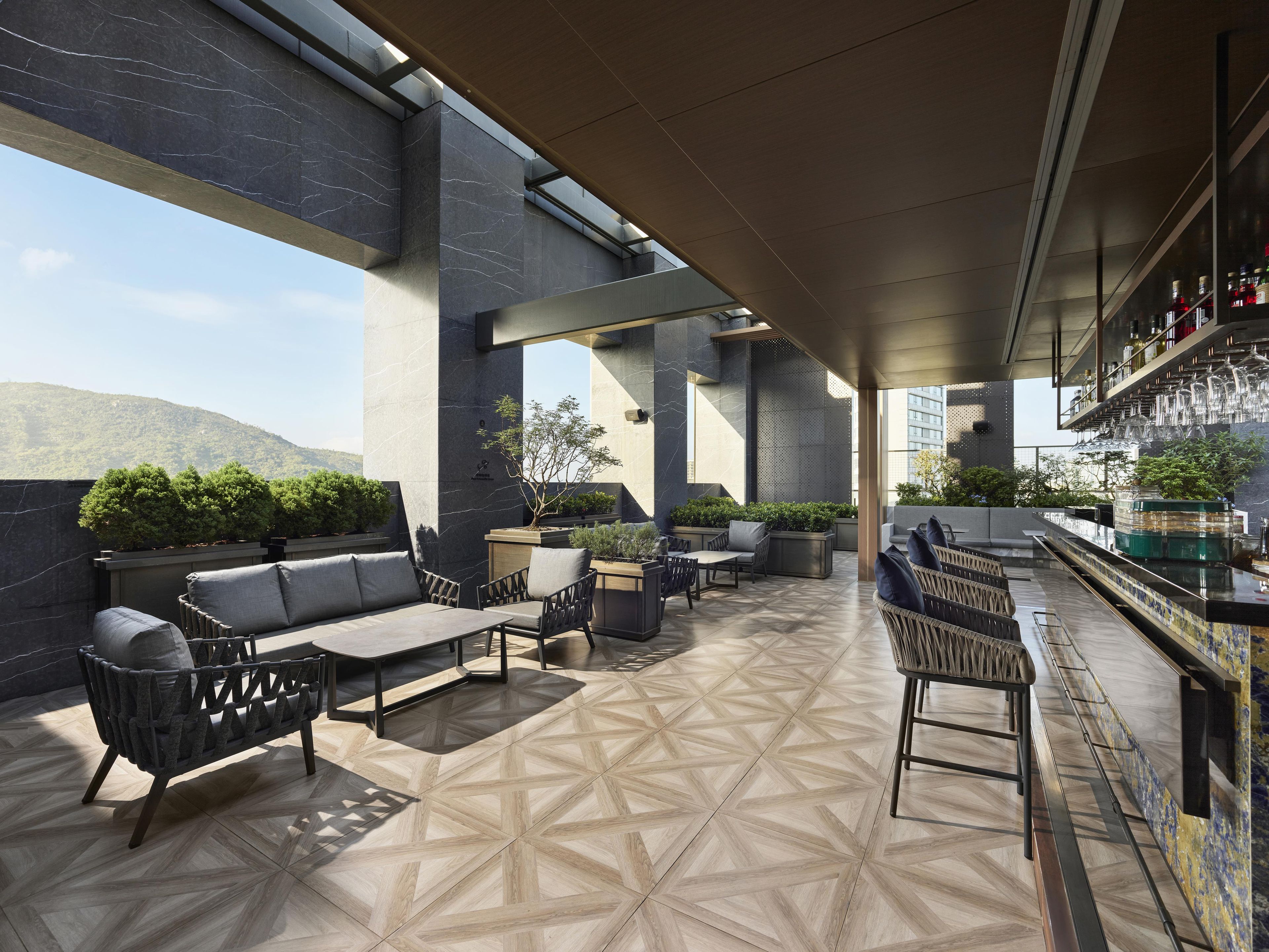 A rooftop bar with outdoor seating, a bar counter, and a view of the city skyline.