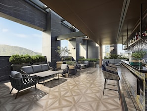 A rooftop bar with outdoor seating, a bar counter, and a view of the city skyline. - Hilton Zhuhai (Zhuhai)