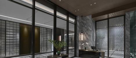 Eine moderne Lobby mit großen Fenstern, einem Marmorboden und einer Rezeption.