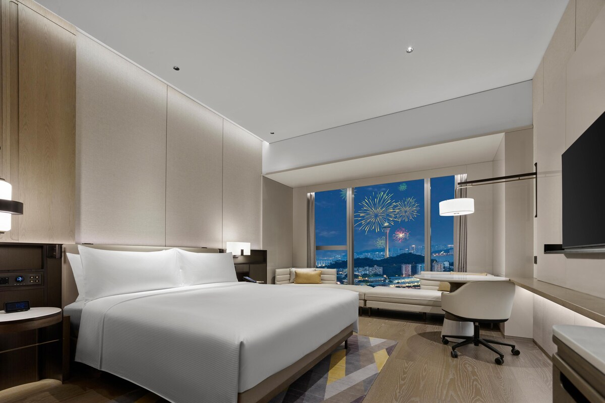 Una habitación de hotel moderna con una cama grande, un escritorio y vistas a fuegos artificiales.