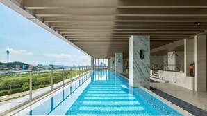 Una piscina interior moderna con vistas despejadas al horizonte de la ciudad y una torre distante.