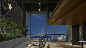 Un comedor moderno con vistas a la silueta urbana, incluyendo una torre, a través de amplias ventanas.
