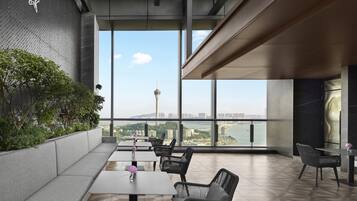 A modern indoor space with a large window overlooking a cityscape, including a tower and a bridge.