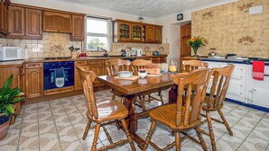 Une cuisine avec des meubles en bois, une table à manger avec des chaises, un four à micro-ondes et une cuisinière.