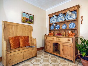 A room with a wooden bench, a cabinet with blue and white plates, and a painting on the wall.