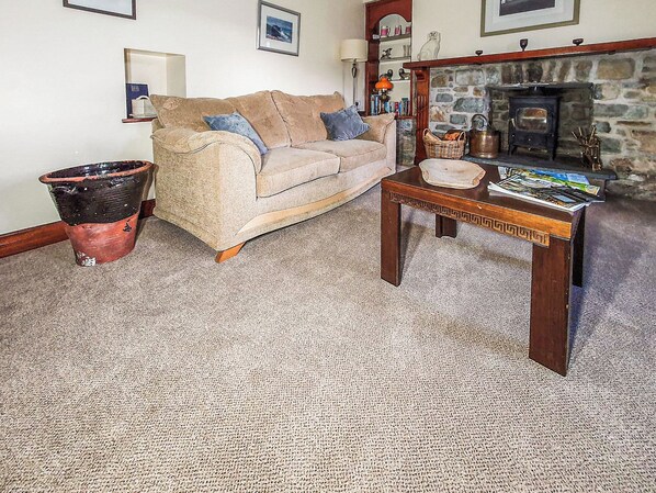 A living room with a sofa, a coffee table, a fireplace, and a stone wall.