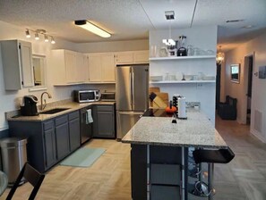 Uma cozinha moderna com armários cinza, eletrodomésticos de aço inoxidável e uma ilha central.