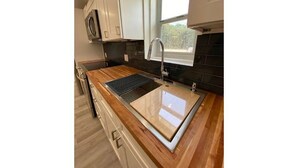 Una cocina moderna con encimera de madera, pileta de acero inoxidable y una ventana sobre la pileta.