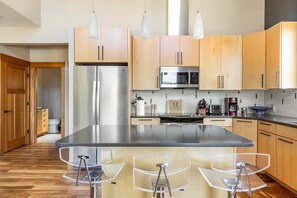 Enjoy cooking in this well-equipped kitchen with a central island, stainless steel appliances, and pendant lights.
