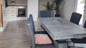 A modern kitchen with a built-in oven and a dining area with a grey table and black chairs.