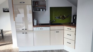 A modern kitchen with white cabinets, a wooden countertop, and a green wall art piece.