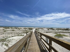 A wooden boardwalk leading to a beach with dunes and a clear sky. - Luxury Beach Condo: Freshly Renovated, Steps from the Ocean, Pool & Hot Tub (St. Augustine Beach)