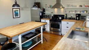 Een moderne keuken met een houten kookeiland, roestvrijstalen apparatuur en een hanglamp.