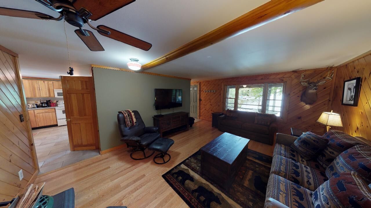 A cozy living room with a ceiling fan, a television, a sofa, and a coffee table.