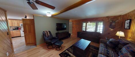 A cozy living room with a ceiling fan, a television, a sofa, and a coffee table.