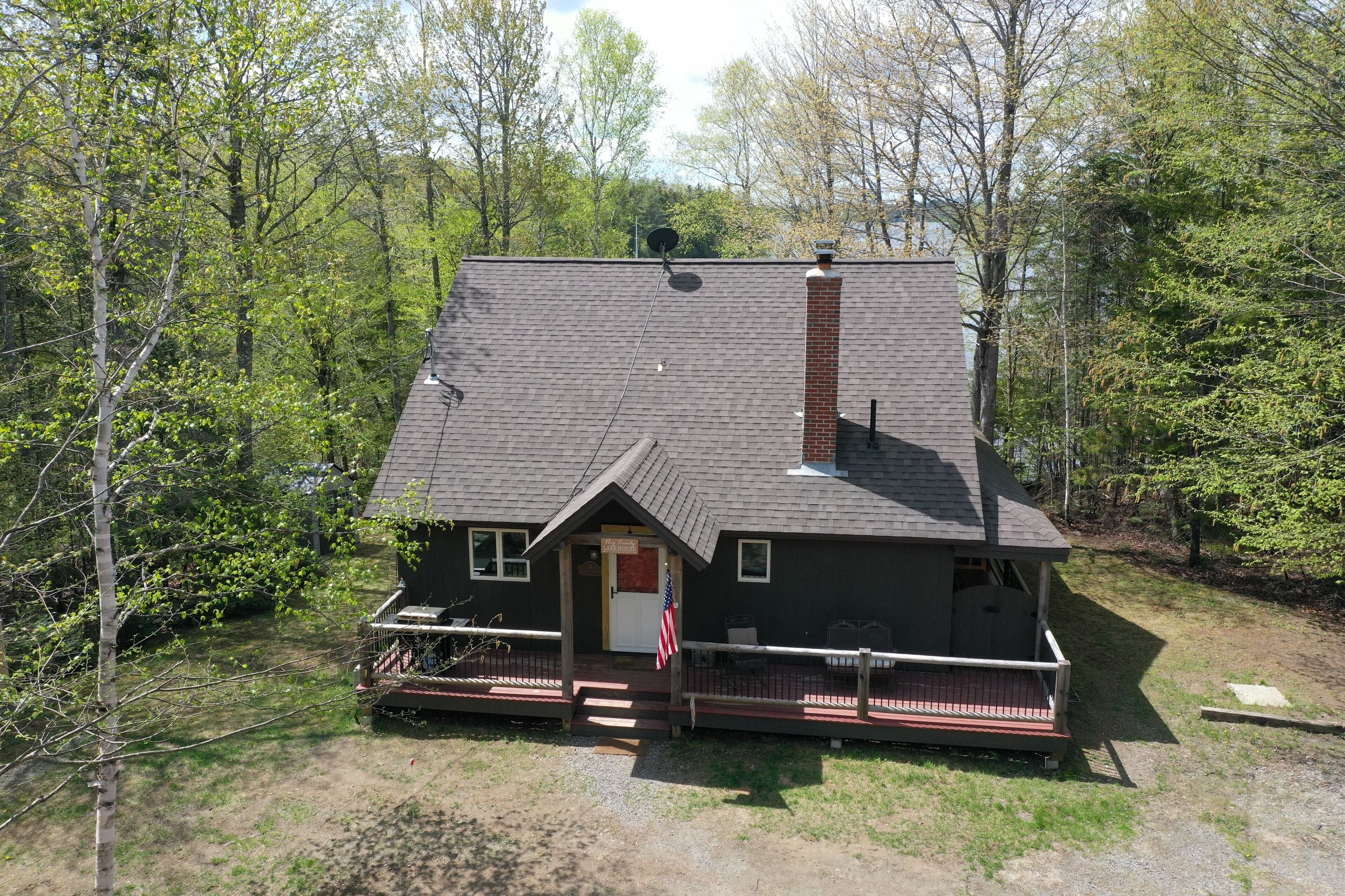 A two-story house with a front porch, a chimney, and a satellite dish.