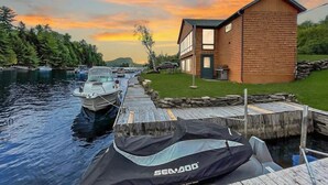 Eine Holzhütte an einem ruhigen Fluss mit angestaubten Booten und einem überdachten Kajak.