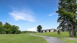 A grassy area with a paved path leading to a building with multiple balconies. - Lakeside Loft (Direct Access to Moosehead Lake!) (Greenville)