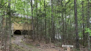 A forested area with a wooden structure labeled 'STONY COVE'. - Stony Cove Camp (Waterfront on Lower Wilson Pond!) (Greenville)