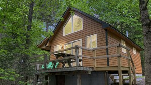 A wooden cabin with a deck, surrounded by trees. - Stony Cove Camp (Waterfront on Lower Wilson Pond!) (Greenville)