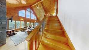 Una scala in legno conduce a un balcone con un muro di pietra su un lato.