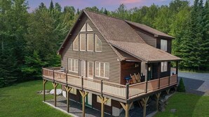Una baita di legno con un balcone, immersa in una foresta.
