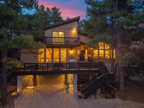 Una cabana de fusta de dos pisos amb un balcó, un porxo cobert i una escala que condueix al pis superior.