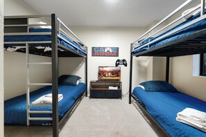 Una habitación con literas, un televisor y un cartel que dice 'GAME ROOM'.