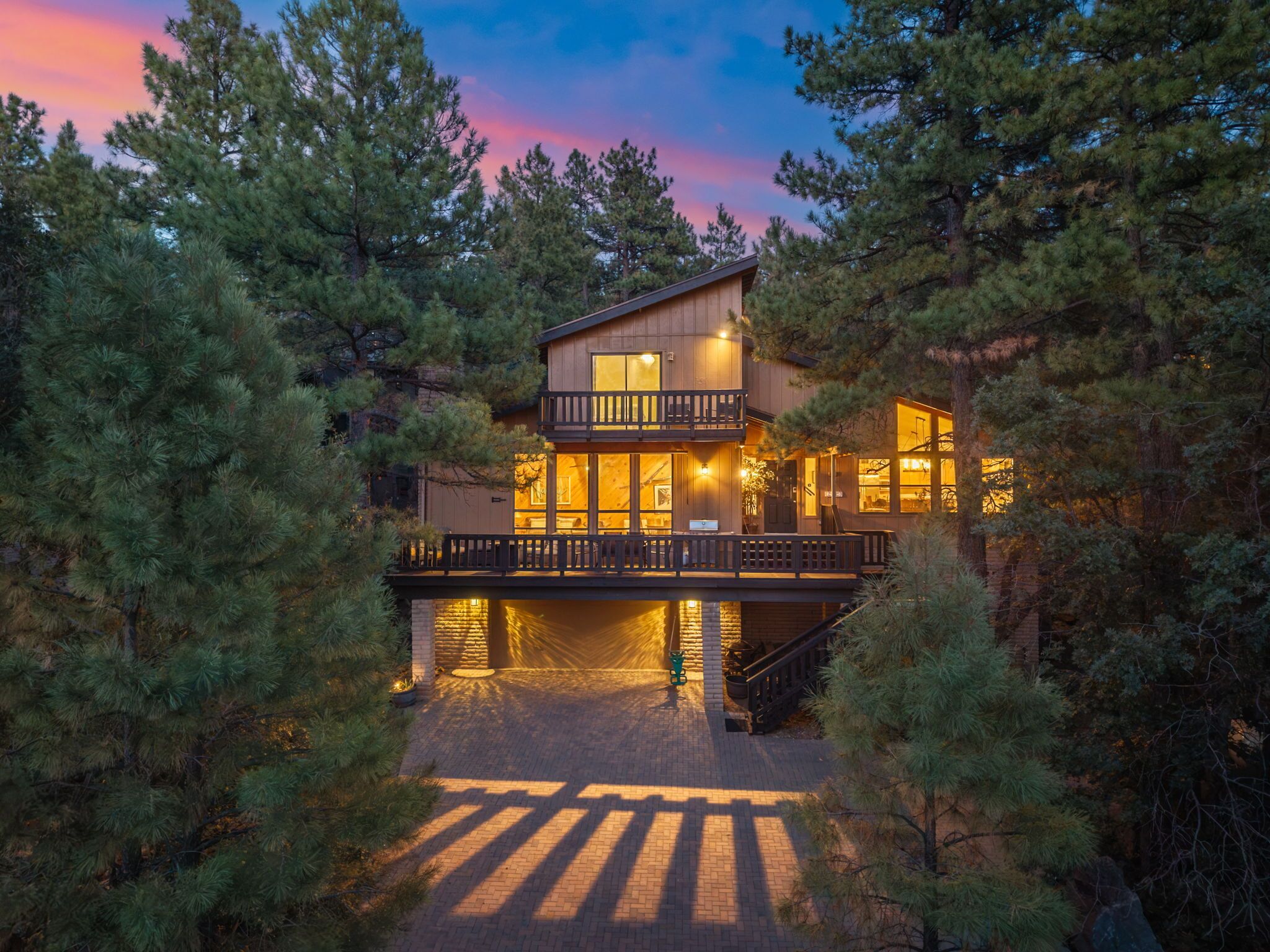 Une cabane à deux étages avec un balcon, entourée d’arbres.