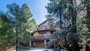 A two-story lodge with a balcony, surrounded by trees and rocks. - Cozy Munds Park Cabin ~ Fire Pit & Sunset Views (Munds Park)
