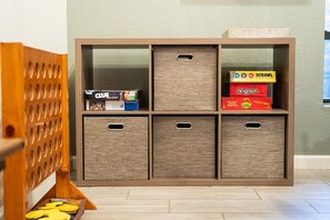 A wooden storage unit with multiple compartments, some containing board games.