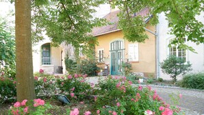 A building with a yellow facade, a green door, and a cobblestone pathway. - Schloss Goldacker - das Schloss der Gesundheit (Unstrut-Hainich)