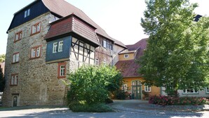 Un edificio europeo tradicional con fachada de piedra, múltiples ventanas y un patio adoquinado.