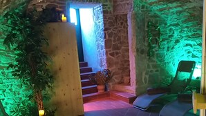 A stone-walled room with a staircase leading to a higher level. There are two massage chairs and a potted plant near the entrance. - Schloss Goldacker - das Schloss der Gesundheit (Unstrut-Hainich)