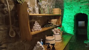 A rustic bathroom with stone walls, wooden shelves, and a green-lit archway. - Schloss Goldacker - das Schloss der Gesundheit (Unstrut-Hainich)