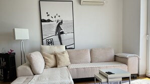 Ein Wohnzimmer mit einem beigefarbenen Ecksofa, einem kleinen Tisch und einem gerahmten Bild an der Wand.