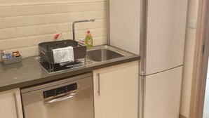 A compact kitchen with a dishwasher, a sink, and a refrigerator. - London Luxury 1 bed flat - kitchen, garden, parking, WIFI (Ilford)