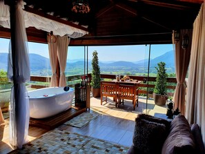 Ein Balkon mit einer Holzbank, einem Tisch mit einer Vase und einer Badewanne.