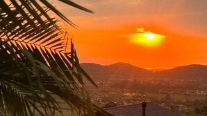 Un atardecer sobre un barrio residencial con una casa de techo inclinado y un pequeño porche.