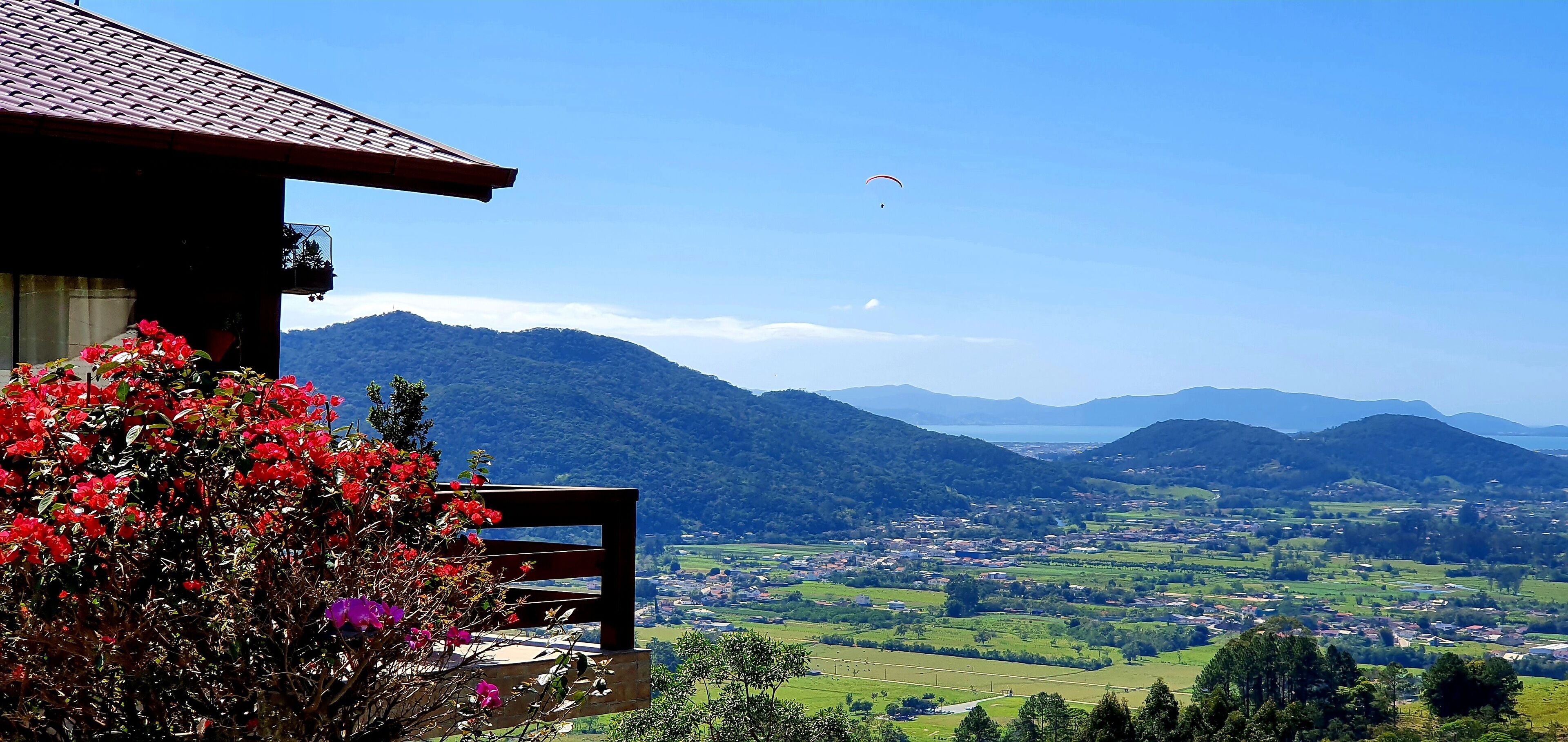 A wooden bench with a view of a valley and mountains.